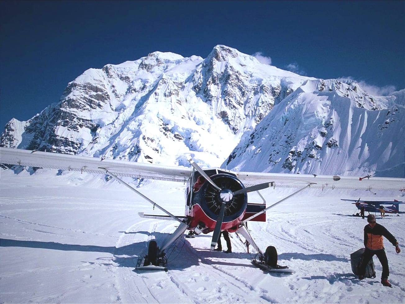 A bush plane unloads climbers and gear on Alaska's Kahiltna Glacier airstrip, the main base camp for expeditions to routes on Mount Hunter, Denali, and Mount Foraker. (AN/J. Heilprin)